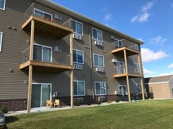 A building with three balconies and a grassy area in front of it